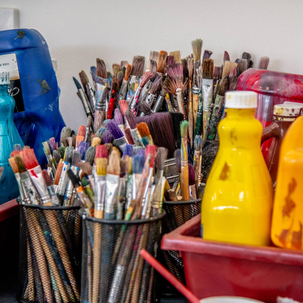 paint supplies including lots of paint brushes and bottles of paints.