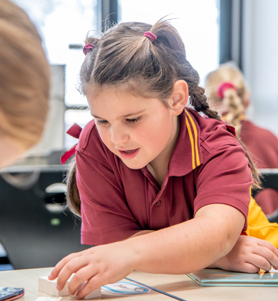 Girl in school uniform inside classroom working on a game