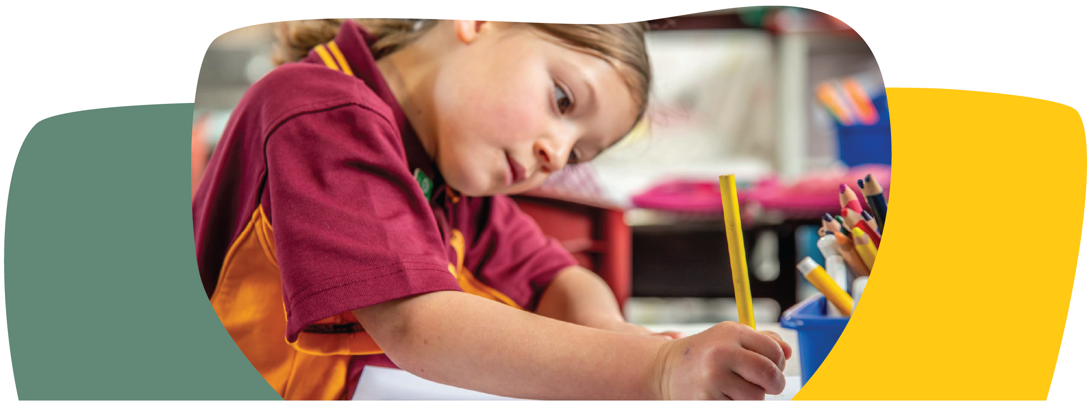 young girl in school setting wearing a maroon coloured top and holding a yellow pencil